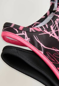 Badeanzug-Oberteil mit schwarzer Basis, pinken abstrakten Mustern, kontrastierendem pinkem Rand und einer strukturierten schwarzen Unterlage.