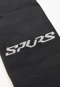 Sort strikket strømpe har ordet "SPURS" i hvid skrift. Texturen er glat med et ensartet stofmønster.