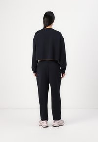 Tengerészeti cropped pulóver hosszú ujjakkal, hozzáillő, tapered fazonú nadrággal párosítva. Az öltözet lazább szabású és puha tapintású.