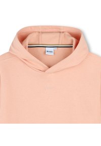 Φούτερ σε ροδακινί απόχρωση με τσέπη καγκουρό, κεντημένο λογότυπο και απαλό υλικό. Το εσωτερικό έχει αντίθετες ρίγες.