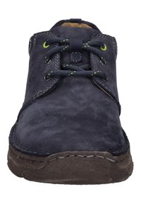 Ciemnoniebieski skórzany but z okrągłym noskiem, kontrastującymi zielonymi oczkami i czarnymi sznurowadłami. Posiada teksturowaną powierzchnię i zaokrągloną brązową podeszwę.