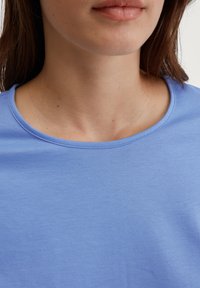 Hellblaues T-Shirt mit Rundhalsausschnitt, aus weichem, glattem Stoff gefertigt. Es hat ein einfaches, sauberes Design mit kurzen Ärmeln.