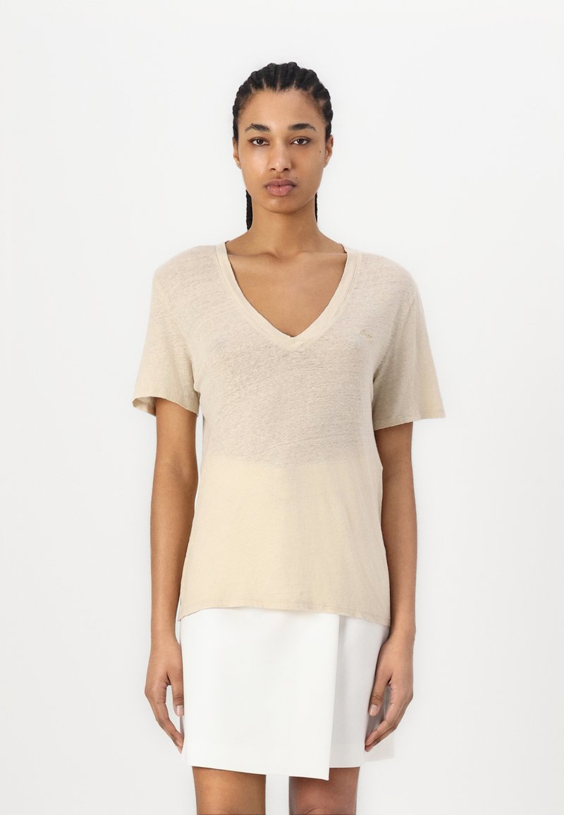 Beige V-nyakú póló rövid ujjakkal, könnyű anyagból készült, enyhén texturált felülettel és laza szabással.