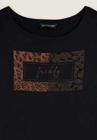 T-shirt nera con una toppa rettangolare decorata da motivi animalier nei toni del marrone e del verde, con il testo "freddy" in lettere metalliche al centro.