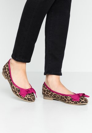 Baleriny w wzór lamparta z różową kokardą, z okrągłym noskiem i niskim obcasem, prezentowane na stopie w czarnych dżinsach.