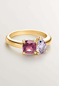 Anillo dorado con una piedra preciosa cuadrada rosa y una piedra preciosa morada en forma de pera, sujetas de forma segura por cuatro garras cada una.