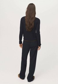 Black knit sweater and matching wide-leg pants, featuring a fitted waist and long sleeves, with a soft texture and minimal design.