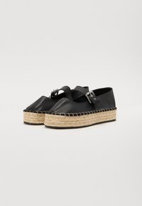 Chaussures espadrilles en cuir noir avec un bout rond, une plateforme en jute caractéristique et une sangle réglable avec une boucle en métal.