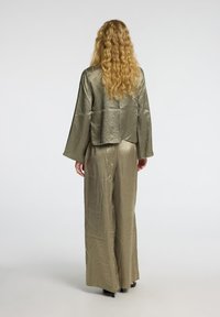 Olive green, satin outfit featuring a cropped, boxy top with wide sleeves and loose, wide-leg pants. Smooth texture, minimal detailing.