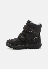 Botte d'hiver pour enfants noirs en textile et matériau synthétique, avec des sangles Velcro et une semelle robuste au motif texturé.