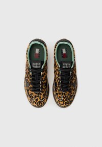 Un paio di sneaker con stampa leopardata, cintura nera, bordi neri e verde menta, e logo Tommy Jeans sulla linguetta e sulla soletta.