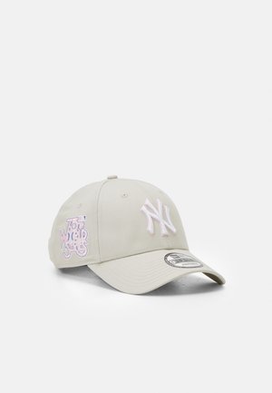 Baseballcap aus beigem Stoff mit einem weißen gestickten "NY"-Logo und rosa Akzenten an der Seite. Gebogener Schirm und verstellbarer Riemen.