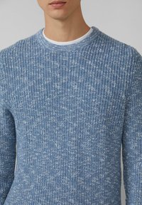 Blauer Strickpullover mit strukturiertem, geripptem Muster. Rundhalsausschnitt mit sichtbarem weißen Akzent darunter. Weicher, mittelschwerer Stoff.
