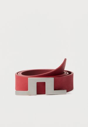 Cintura rossa in pelle arrotolata con una fibbia rettangolare in metallo argento con un centro ritagliato su sfondo bianco.