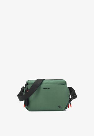 Zelená obdĺžniková crossbody taška s čiernym nastaviteľným popruhom, čiernym logom Hedgren a priehradkami na zips s červenými ťahadlami.