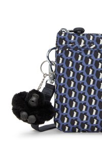 Borsa a fantasia blu navy e bianca realizzata in tessuto, con chiusura a zip e un portachiavi a forma di gorilla di pelliccia nera attaccato con una catena metallica.