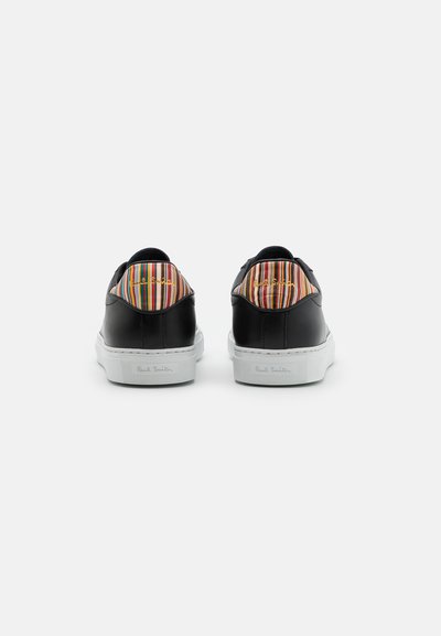 Black leather sneakers with a textured white sole, featuring a multicolored striped accent on the heel and embossed branding on the side.
