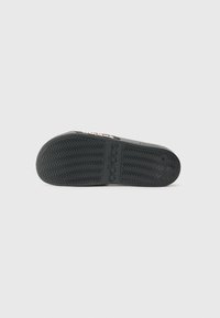 Black rubber shoe sole featuring a zigzag traction pattern and embossed logo detailing, with a flat profile and round toe design.