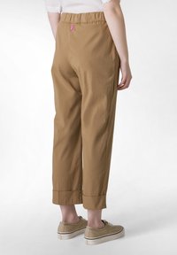 Brązowe, lekkie spodnie z elastycznym paskiem w talii, z krojem 7/8 i podwiniętymi mankietami. Zawierają różowy detal z logo z tyłu.