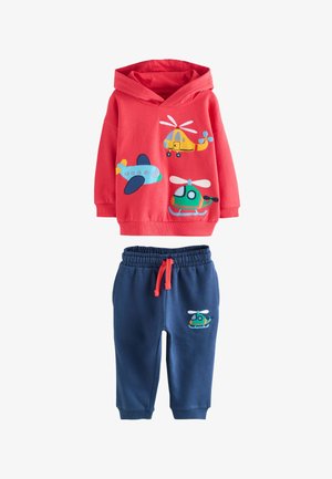 Czerwona bluza z kapturem z kolorowymi wzorami samolotów i helikopterów, zestawiona z granatowymi spodniami z małą grafiką helikoptera i czerwonym ściągaczem.