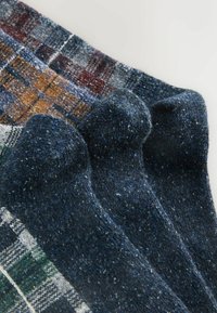 Uldstrømper i nuancer af marineblå og grå med varierende mønstre, herunder tern og ensfarvede teksturer. Har ribbede mansjetter og blødt, fuzzy stof.