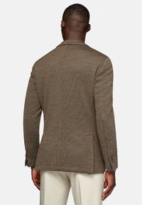 Brown textured blazer with a single back vent, notched lapels, and two-button closure, featuring a smooth finish and tailored sleeves.