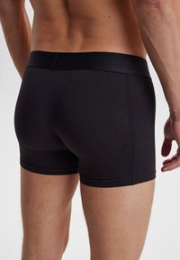 Schwarze Baumwoll-Boxershorts mit passgenauer Schnittführung und elastischem Bund. Der Stoff ist glatt und matt, ohne sichtbare Muster oder Logos.