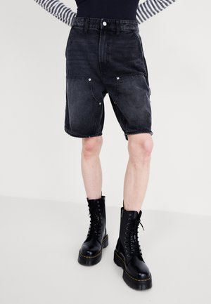 Czarne szorty dżinsowe z wysokim stanem, z przednimi kieszeniami i srebrnymi dodatkami. Stylizowane z czarnymi botkami na sznurowanie.