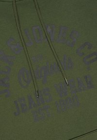 Dark green hoodie featuring a front print in a lighter shade, detailing “Jack & Jones Co.”, “MFG Originals”, and “JEANS WEAR EST. 1990.”