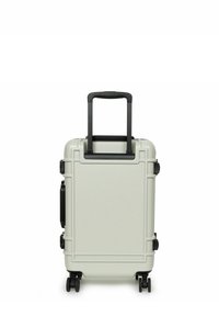 Tvrdý kufr světle šedé barvy s černými akcenty, vybavený teleskopickou rukojetí, čtyřmi kolečky a vyztuženými rohy pro zvýšenou odolnost.