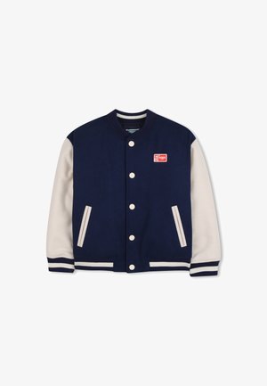 Veste universitaire bleu marine avec manches crème, poignets et col côtelés. Comprend un écusson logo rouge et des boutons-pression blancs. Tissu texturé.