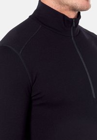 Czarny rozpinany polar wykonany z gładkiego materiału, z wysokim kołnierzem i płaskimi szwami, z subtelnymi szarymi akcentami ściegów.