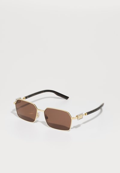Brown tinted sunglasses with an angular gold metal frame, featuring black plastic temples and square accents on the front.