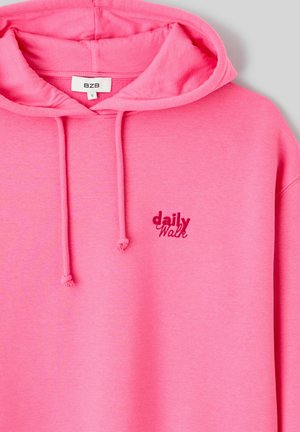 Sweat à capuche rose en tissu doux, doté d'une capuche à cordon et du texte brodé "daily Walk" en rose foncé. Design simple sans motifs.