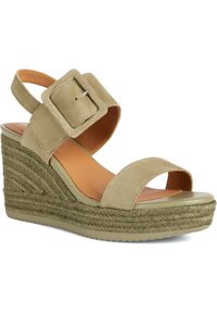 Sandalias de cuña de ante color beige con una amplia tira en el tobillo y una gran hebilla cuadrada. Plataforma envuelta en yute y suela de goma lisa.