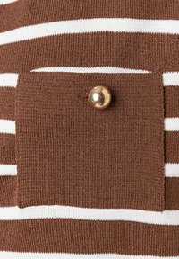 Braun- und weiß gestreifter Strickstoff mit einer quadratischen Tasche und einem goldenen Knopfakzent. Die Textur ist glatt und leicht dehnbar.