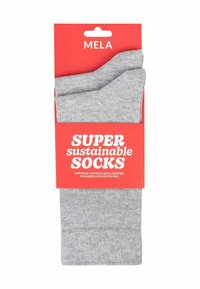 Grijze katoenen sokken met een gladde textuur, verpakt met een helder rood label waarop staat "SUPER duurzame SOKKEN." Fairtrade-gecertificeerde materialen.