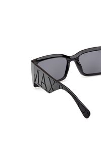 Gafas de sol negras con un diseño rectangular, lentes grises y brazos texturizados con la inscripción grabada "MAXO." Acabado suave y brillante.