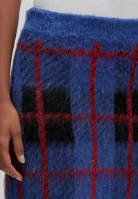 Wollen rok met een blauw en zwart ruitpatroon met rode lijnen. Gestructureerde, fuzzy afwerking en een brede elastische tailleband.