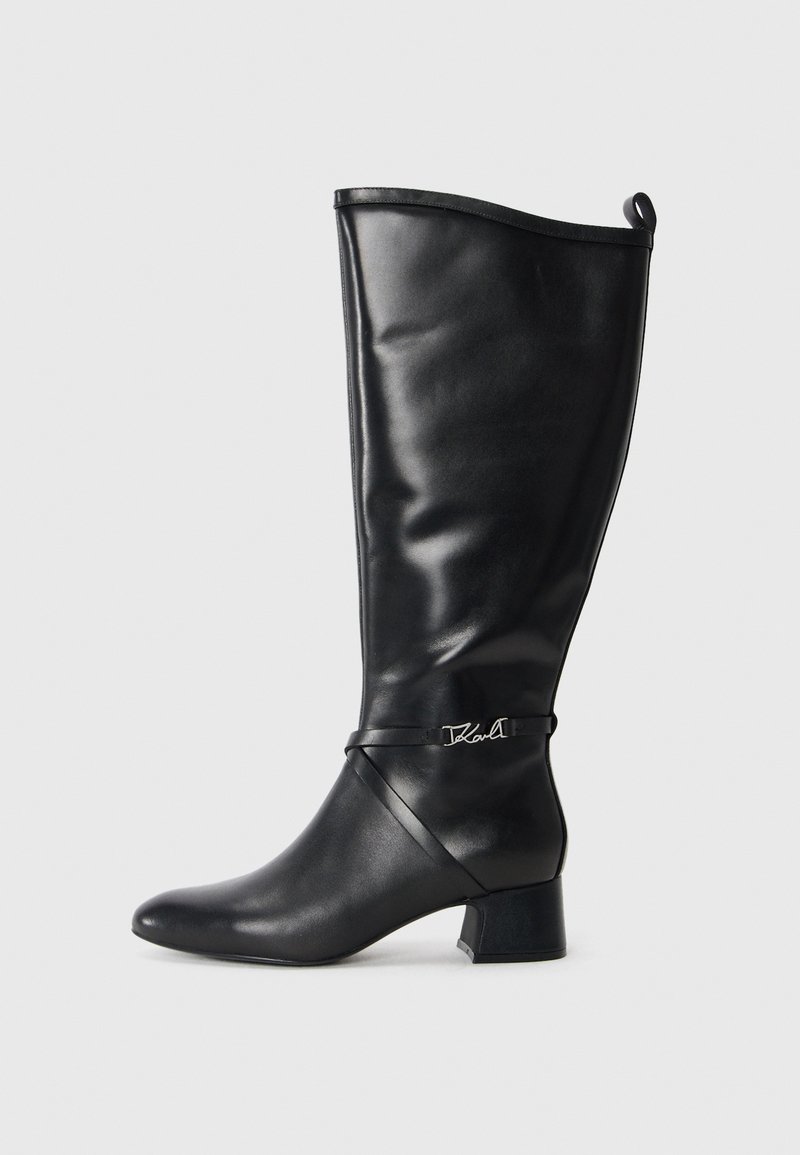 Czarne skórzane kozaki do kolan z zaostrzonym noskiem, wykładanym obcasem oraz dekoracyjnym paskiem z srebrnym logo w okolicy kostki. Gładka tekstura.