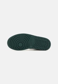 Nikeova potplatica s teksturiranim gumama u tamnozelenoj boji s kružnim i linearnih uzorcima, te s centralnim logotipom utisnutim sa strane.