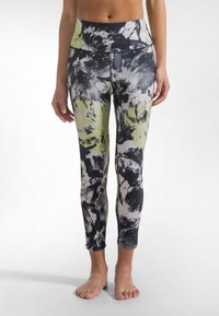 Flerfärgade leggings med hög midja, abstrakta mönster i svart, vitt och limegrönt, tillverkade av elastiskt och luftigt tyg.