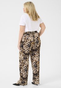 Spodnie o wysokim stanie, luźne, w leopardzi wzór w odcieniach brązu, czerni i kremu, zestawione z podstawowym białym t-shirtem.