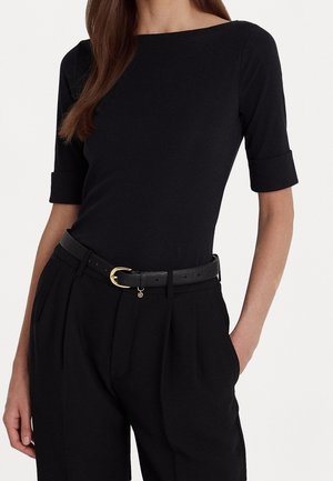 Black fitted top with a wide neckline and short rolled sleeves, paired with high-waisted black pleated trousers and a black belt featuring a gold buckle.