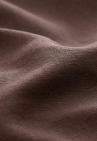 Tissu marron doux avec une texture subtile et des plis doux créant des vagues lisses et fluides sur toute la surface.