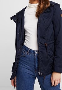 Marineblaue, leichte Jacke mit Reißverschluss, verstellbarem Taillenzug und zwei Fronttaschen. Glatte Textur und lässiges Design.