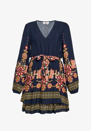 Vestido azul marino con mangas largas, escote en V, bordado floral en rojo y amarillo, dobladillo con volantes en capas, cinturón acentuado. Tejido ligero.