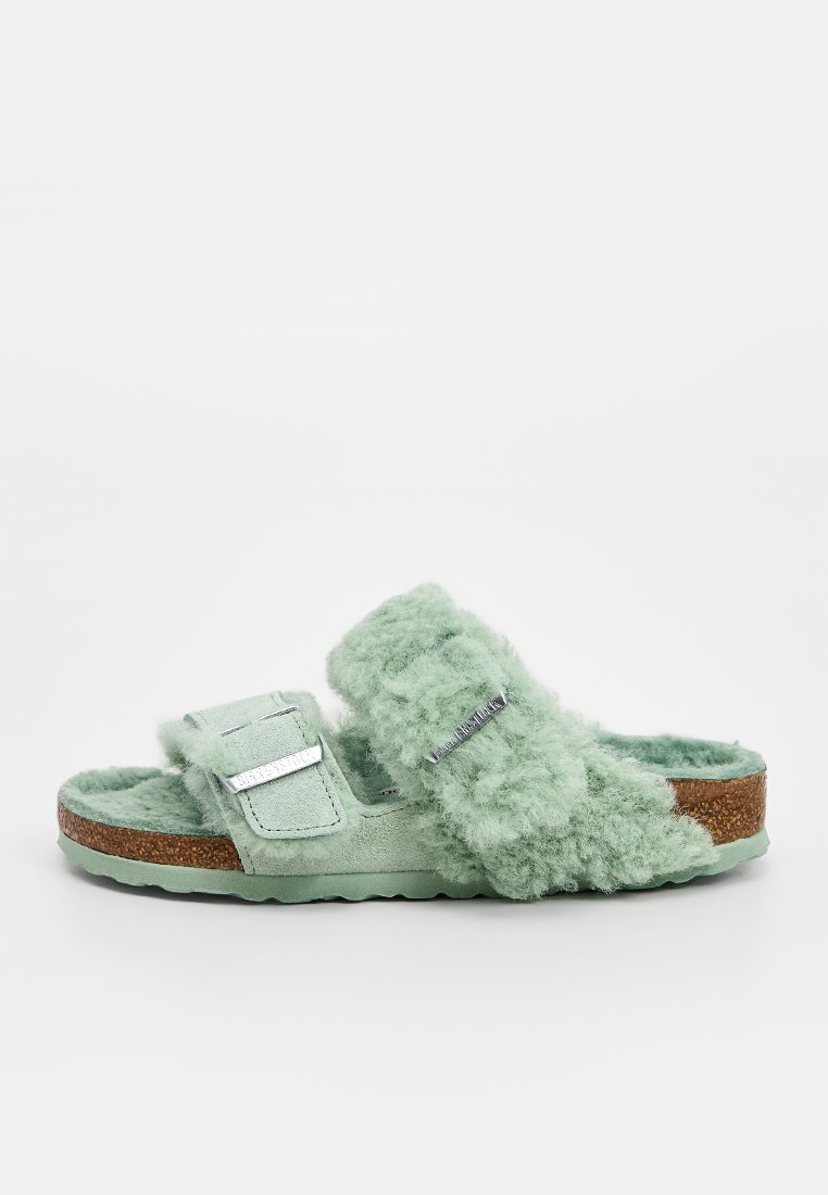 Grüne Slide-Sandalen mit einem weichen, flauschigen Obermaterial und Wildleder-Riemen. Ausgestattet mit einem Korkfußbett und einer Gummisohle sowie verstellbaren Riemen.