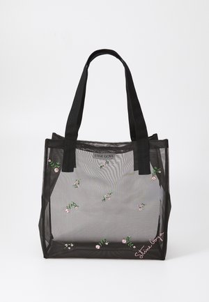 Bolso de malla negra con patrones florales bordados, que cuenta con asas negras resistentes y una etiqueta de logo en la parte delantera. Material translúcido.
