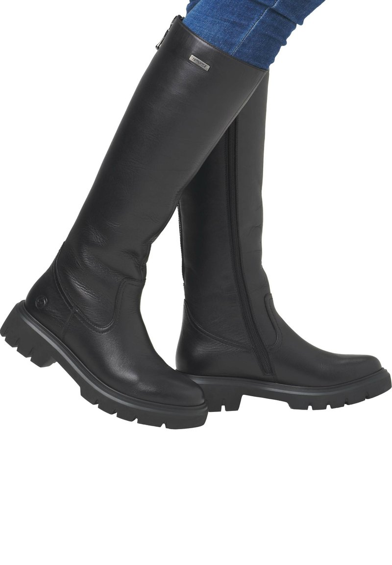 Schwarze knöchelhohe Stiefel aus glattem Leder mit einem seitlichen Reißverschluss, dicken Gummisohlen und subtilen Stitching-Details entlang des Designs.